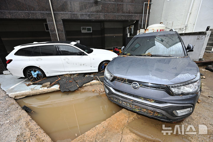 폭우 뒤 파손된 도로 주변에 놓인 차량들