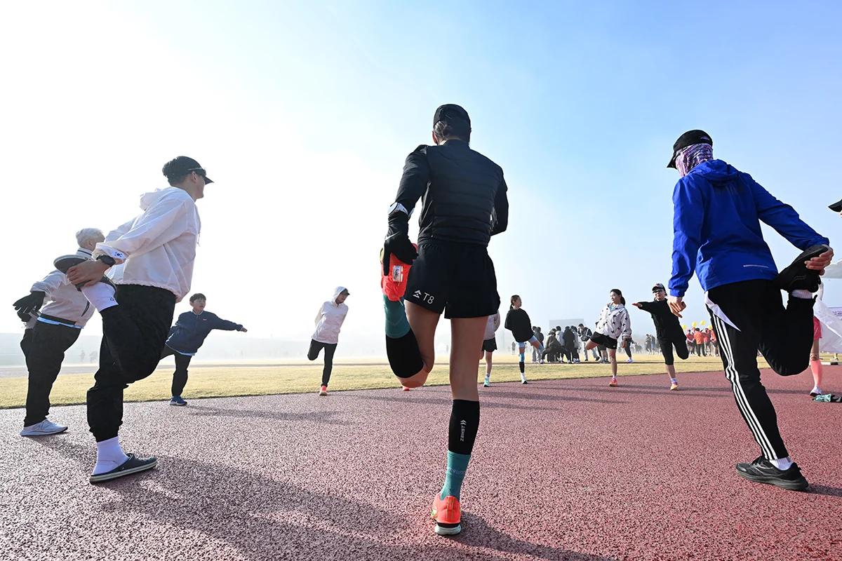 나주영산강마라톤 출발 전 트랙에서 한쪽 다리를 접어 스트레칭하는 참가자들
